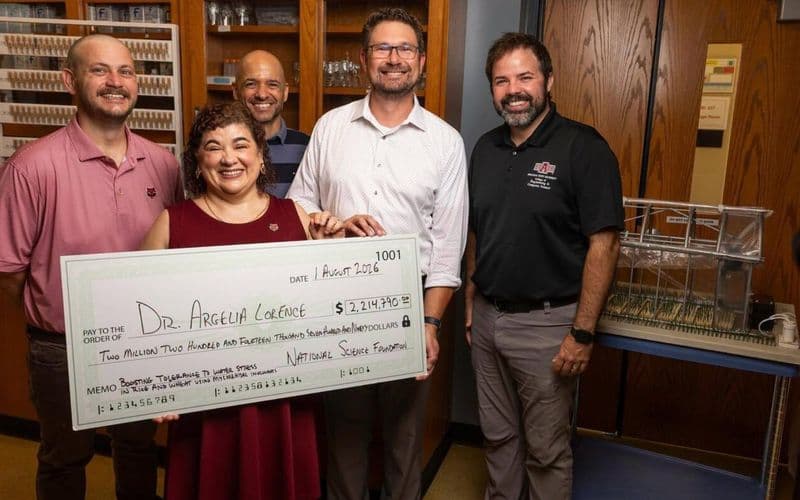 Dr. Argelia Lorence holding the ceremonial National Science Foundation cheque for $2,214,790 with four colleagues in the Arkansas Biosciences Institute laboratory