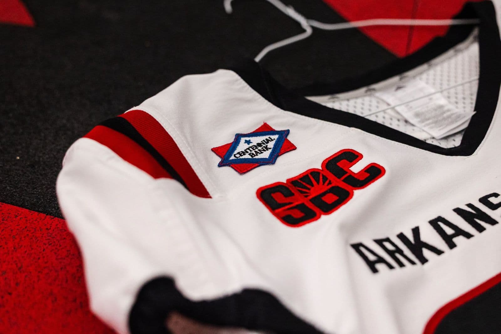 Close-up of the Centennial Bank patch stitched on the white Arkansas State Red Wolves football jersey, next to the Sun Belt Conference logo