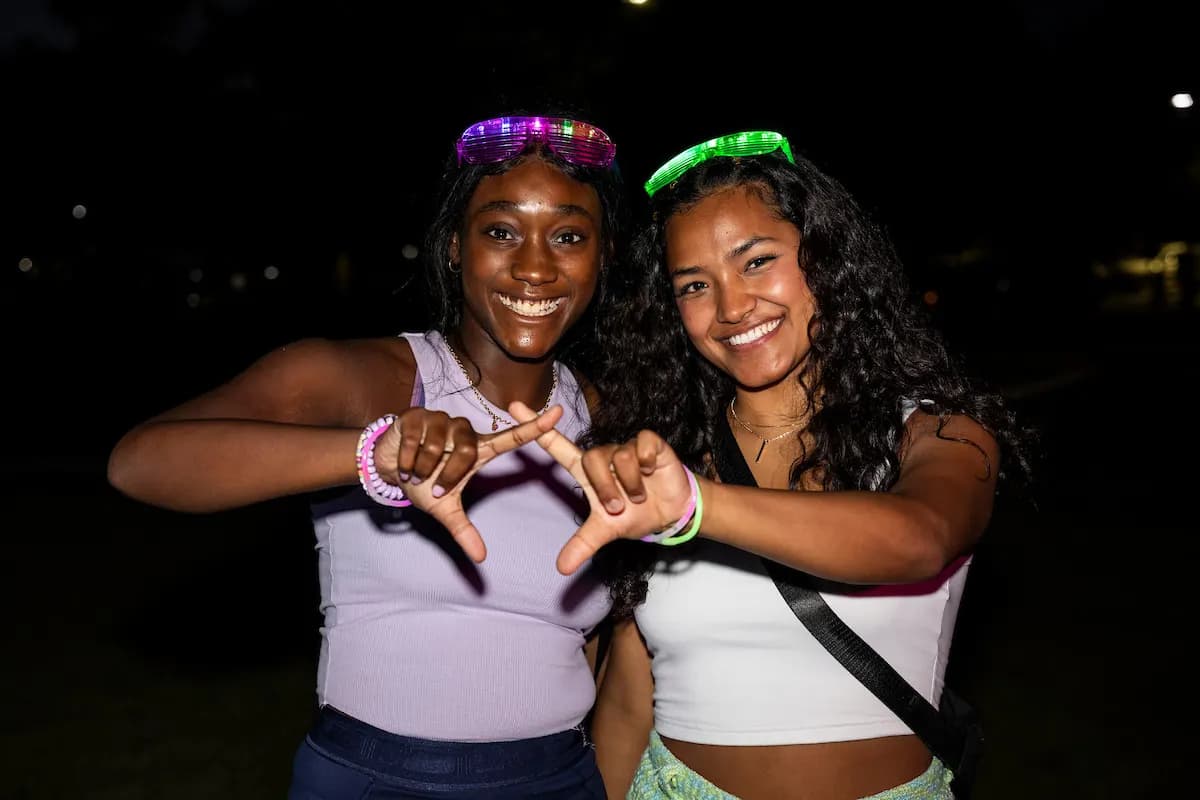 Students holding glowing lights at an evening event on the campus lawn
