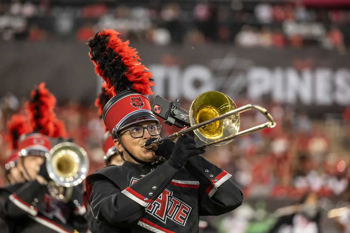 A trombone player in the A-State marching band performing at a football game