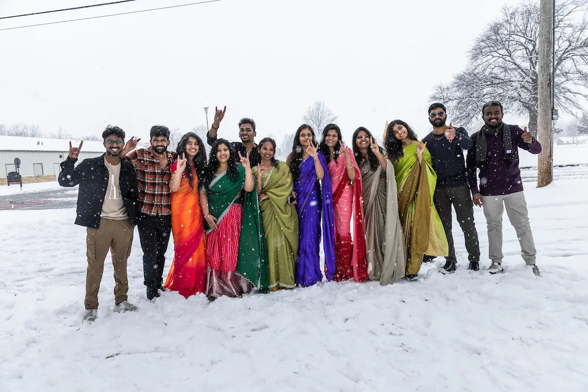 International students at A-State in colourful traditional dress on a snowy day on campus