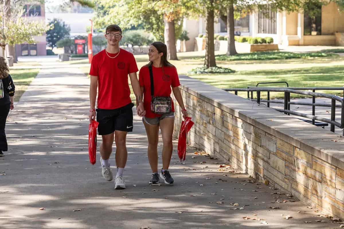 Two A-State students walking across campus in red shirts