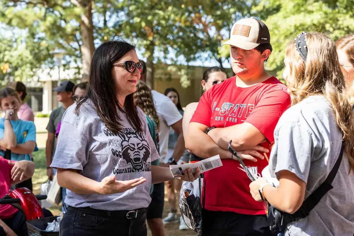 An A-State staff member talking with students at a campus event