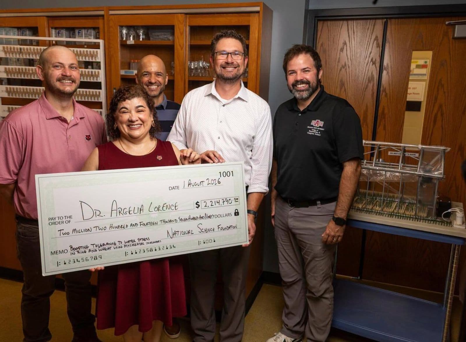 Dr. Argelia Lorence holding the ceremonial National Science Foundation cheque for $2,214,790 with four colleagues in the Arkansas Biosciences Institute laboratory